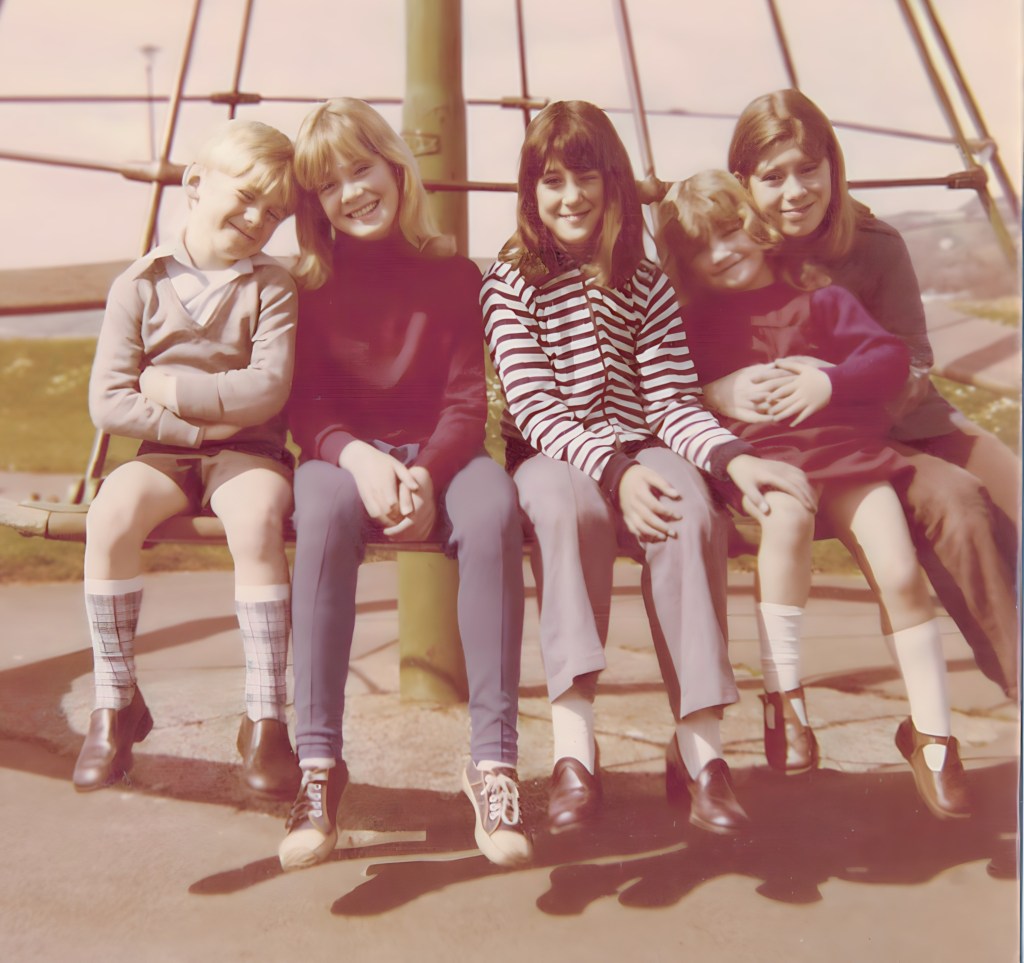 This image shows me with my four sisters sat on a Witch's Hat roundabout in a park in Teignmouth